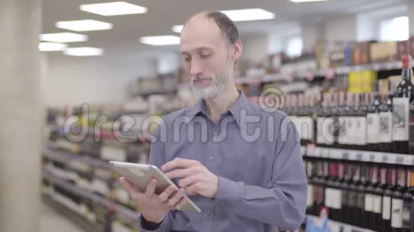 酒精超市使用平板电脑的专业高级交易员画像充满自信的白种人留着胡子的人视频的预览图