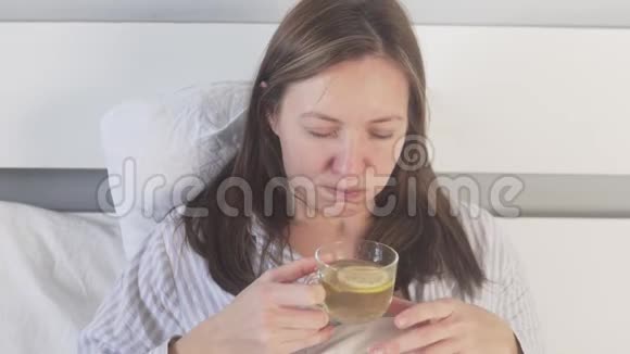 一个生病的女人在家里的床上喝着柠檬茶视频的预览图