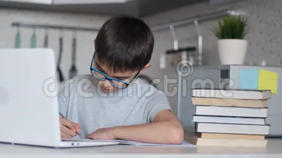 肖像一个孩子在餐桌旁的厨房里坐着用笔记本电脑做作业用一个视频的预览图