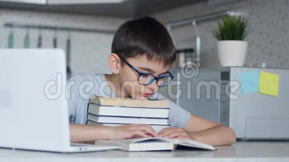 一个孩子通过阅读一本教科书来做家庭作业他的头靠在一堆教科书上视频的预览图