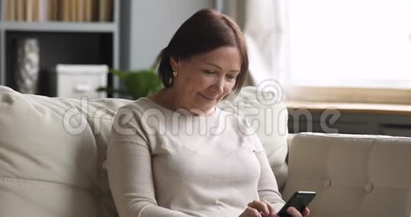 快乐的中年黑发女人使用移动应用程序视频的预览图