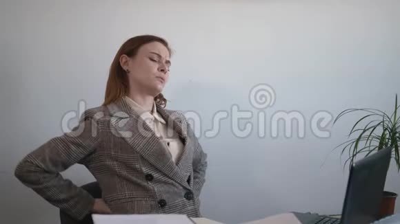健康方面女商人在办公室工作时坐在电脑旁因姿势不当而背痛视频的预览图