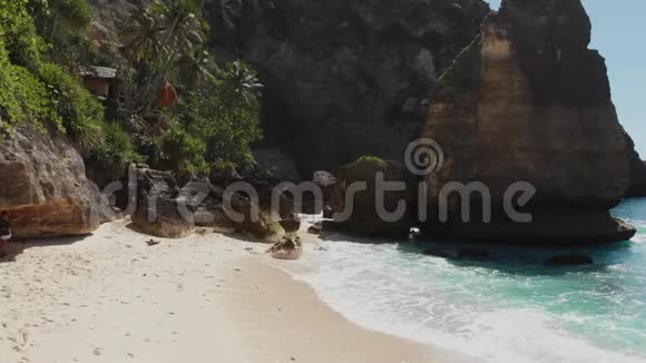后景女子比基尼漫步在海滩与海石和绿松石海洋蓝天努萨佩奈达Atuh海滩视频的预览图