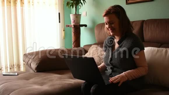 中年妇女在家里通过互联网在笔记本电脑上聊天视频的预览图
