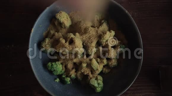 在厨房桌上的一个碗中加入西兰花并加入调味料混合烹饪视频的预览图