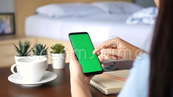 4K在家中用绿色屏幕关闭女性手握手机智能手机在手机屏幕上滑动手指以读取内容视频的预览图