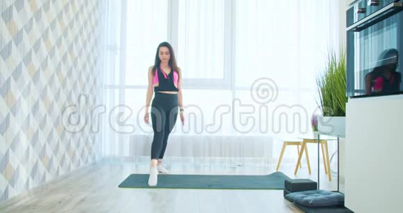 年轻的黑发女人正在瑜伽垫上做分裂动作灵活的体操运动员4k视频的预览图