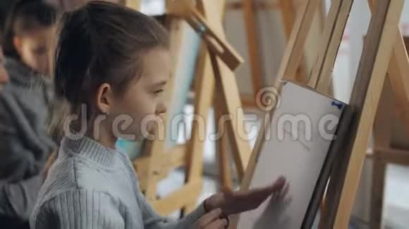 在艺术工作室里女孩的特写在画架上画了一幅铅笔素描视频的预览图