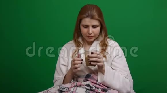 特写镜头生病的女人穿着浴袍裹着温暖的毯子喝着热茶COVID2019年冠状病毒大流行的危险视频的预览图