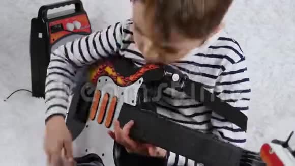 一个快乐的学龄前男孩演奏一把活跃的节奏吉他幼儿发展和游戏音乐创造力视频的预览图