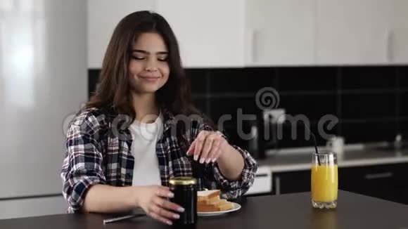 检疫期间厨房里的年轻女子把一些果酱从罐子里放在烤面包上然后涂上油脂早上早餐视频的预览图