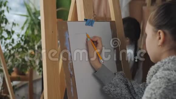 一个拿着铅笔的少女在艺术学校里坐在画架上画着静物视频的预览图