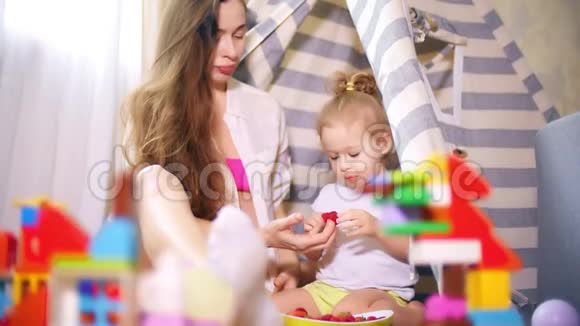 美丽的孕妇和她的小宝宝在玩具帐篷里吃树莓视频的预览图