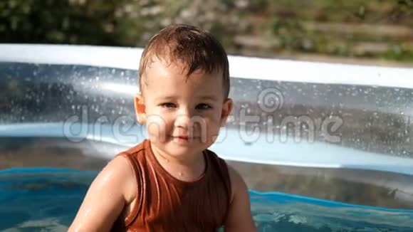 坐在室外游泳池里的小白种人男孩的慢镜头肖像视频的预览图
