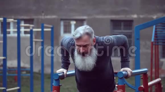 大胡子的老人强壮的手臂在户外锻炼做拉力运动老年男性在霍里做拉力运动视频的预览图