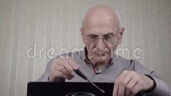 戴眼镜的老人在家里给黑色电视机安装螺丝视频的预览图