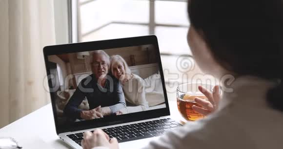 女儿视频打电话给老父母在网络摄像头聊天笔记本电脑视频的预览图