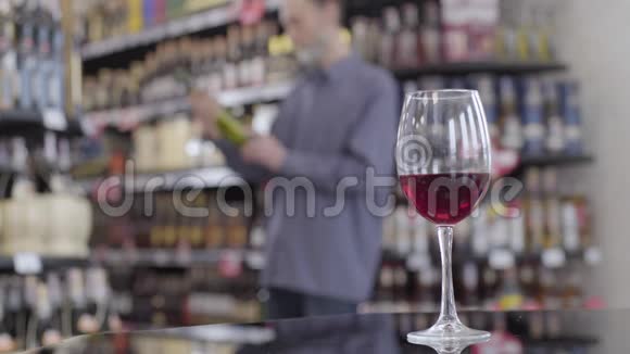 桌上摆放着酒杯的特写镜头背景是模糊的白种人正在检查一瓶白酒视频的预览图