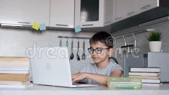 带着眼镜的男孩带着课本在学校做作业在家里用笔记本电脑在线学习远程学习视频的预览图