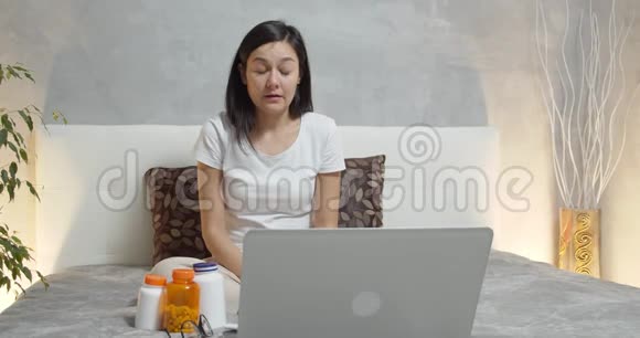 年轻生病的女人坐在床上用手帕打喷嚏寒冷或过敏视频的预览图