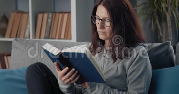 坐在沙发上看书的轻松女人视频的预览图