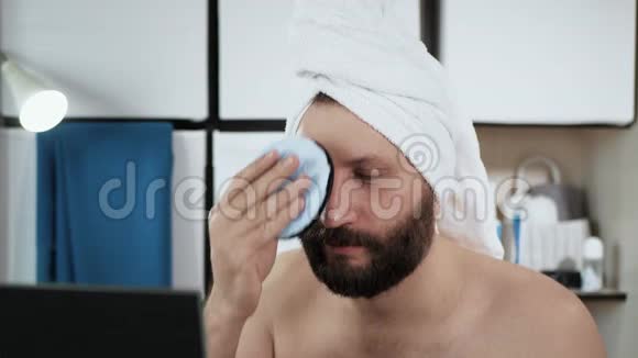 人用海绵洗脸可爱的年轻白种人在浴室里照镜子擦脸视频的预览图