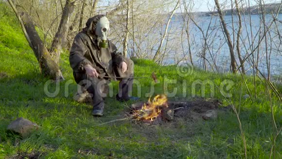 一个戴防毒面具的人在篝火旁炸香肠视频的预览图