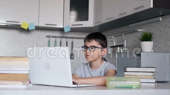 带着课本在学校做作业的男孩在家里用笔记本电脑在线学习远程学习家庭教育视频的预览图
