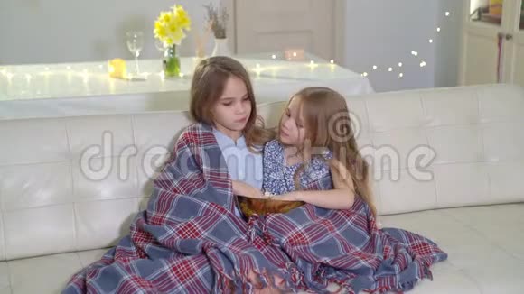 穿毛毯的姐妹们坐在沙发上吃爆米花看电视视频的预览图