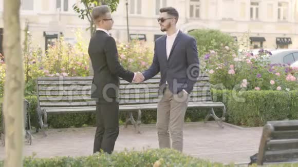 两个穿西装的白种人年轻人在户外见面握手作为禁止标志出现社会的重要性视频的预览图