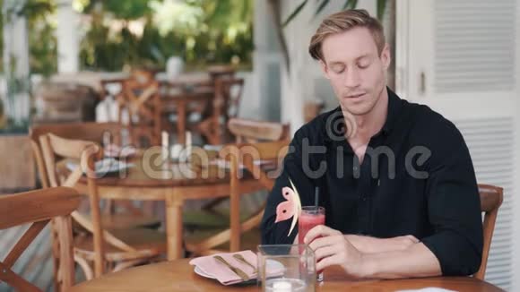 帅哥在时尚咖啡馆喝西瓜汁看着镜头微笑着视频的预览图