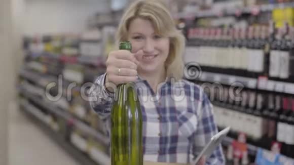 焦点从笑容满面的白人金发女人到镜头前的一瓶白葡萄酒视频的预览图