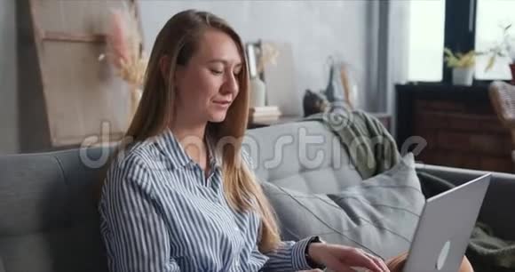 幸福健康的年轻金发女人在社交距离期间使用笔记本电脑在家工作的特写肖像视频的预览图