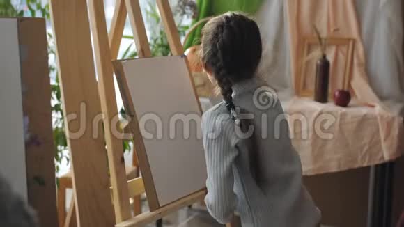 艺术工作室的老师教孩子们坐在画架前的女孩仔细听老师的话视频的预览图