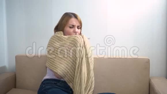 Bola女孩坐在沙发上用毯子盖着自己打喷嚏视频的预览图