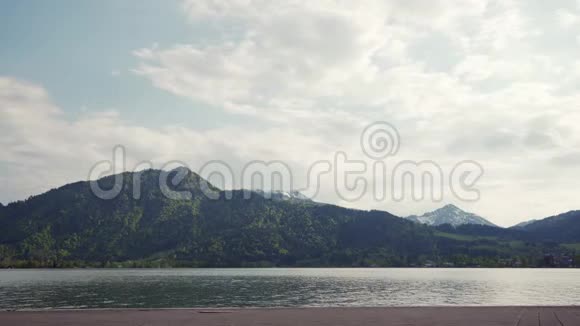 情侣们沿着Tegernsee湖堤走着可以看到阿尔卑斯山的风景视频的预览图