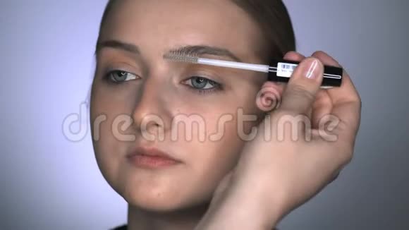 化妆师在美容工作室为年轻女性做专业化妆的宏观镜头化妆师用刷子视频的预览图