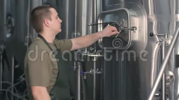 一个男性酿造者从啤酒罐中抽出废麦芽来酿造啤酒啤酒生产视频的预览图