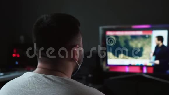 男性在家观看有关冠状病毒的新闻视频的预览图