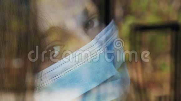 一个戴着医用口罩的少女望着窗外视频的预览图