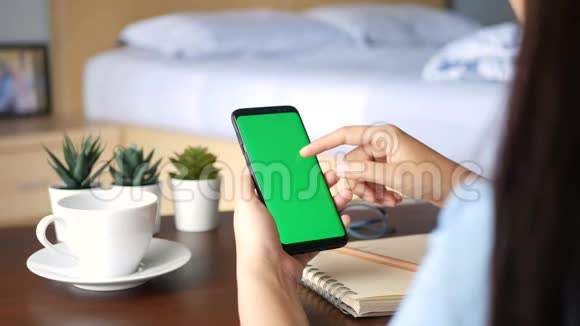 4K在家中用绿色屏幕关闭女性手握手机智能手机在手机屏幕上滑动手指以读取内容视频的预览图