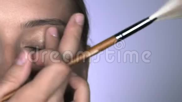 化妆师在美容工作室为年轻女性制作专业化妆的宏观镜头化妆师用手指视频的预览图