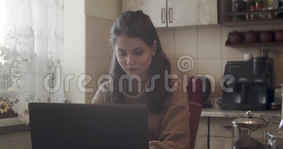 有魅力的女人在家里厨房用笔记本电脑工作视频的预览图