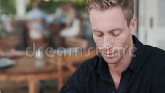 帅哥在咖啡馆里喝着杯子里的热饮料和微笑的肖像视频的预览图