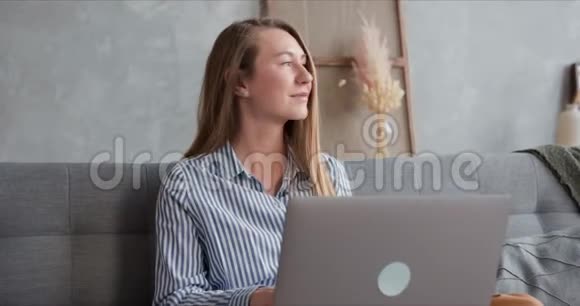 快乐健康的年轻金发女人在家使用笔记本电脑在线购物并在隔离期间在家工作视频的预览图