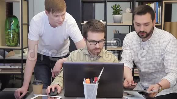 同事在办公室里为坐在笔记本电脑后面的工作计划解释视频的预览图
