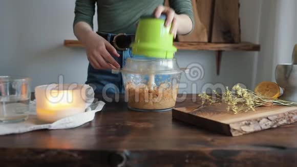 一个年轻的女孩在搅拌机里加水把所有的原料混合在一起得到自制的鹰嘴豆泥特写视频的预览图
