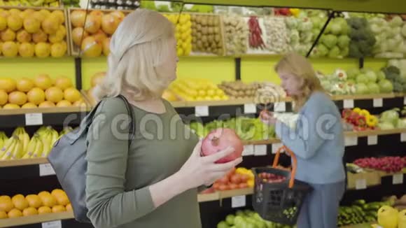 成熟白种人妇女与朋友建议购买多汁有机石榴的肖像严肃的家庭主妇视频的预览图