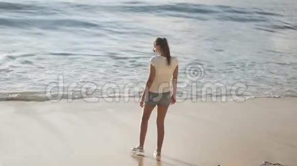 背面的女人看海滩上的海洋张开双臂视频的预览图