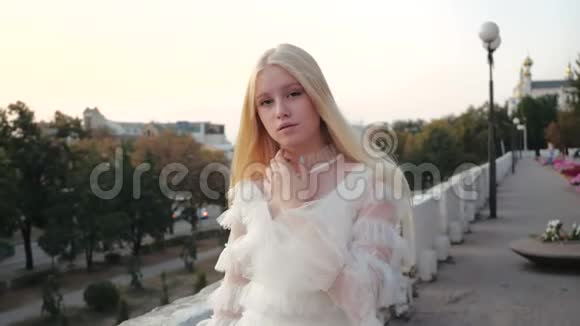 美丽的白种人少女穿着白色的风衣在日落时走在街上化妆的审美时尚模特视频的预览图
